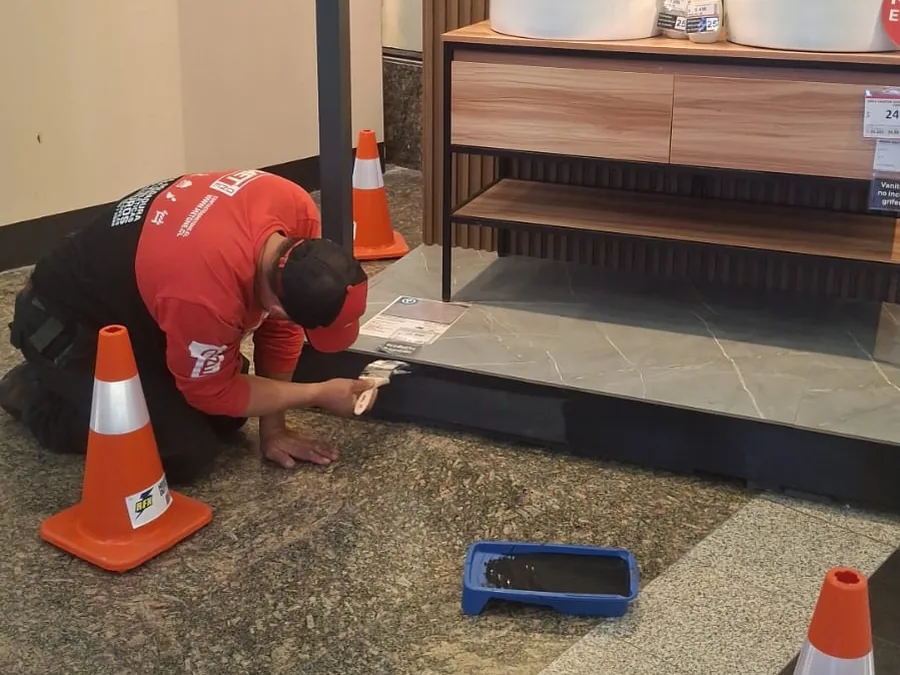 Técnico de MET ONE ejecutando una reparación en sala de ventas con señalización de seguridad