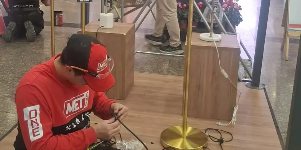 Técnico de MET ONE reparando una lámpara en el pasillo de un centro comercial